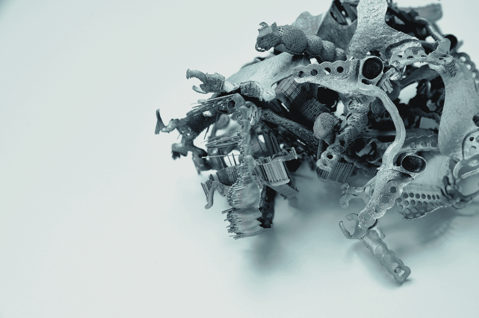 Viele unterschiedliche Metallteile aus der additiven Fertigung liegen als Ausschuss gesammelt auf einem Haufen bei Laser Add Concept
