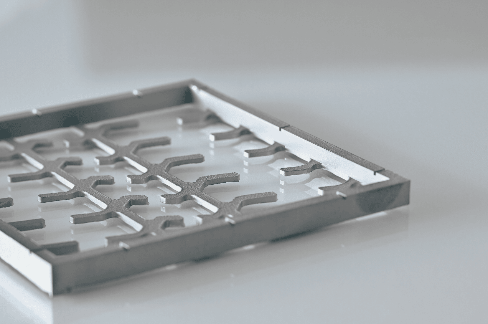 Ein einzelnes Metallbauteil aus dem 3D Druck Titan liegt auf einer neutralen Fläche und wurde als Produktfoto aufgenommen
