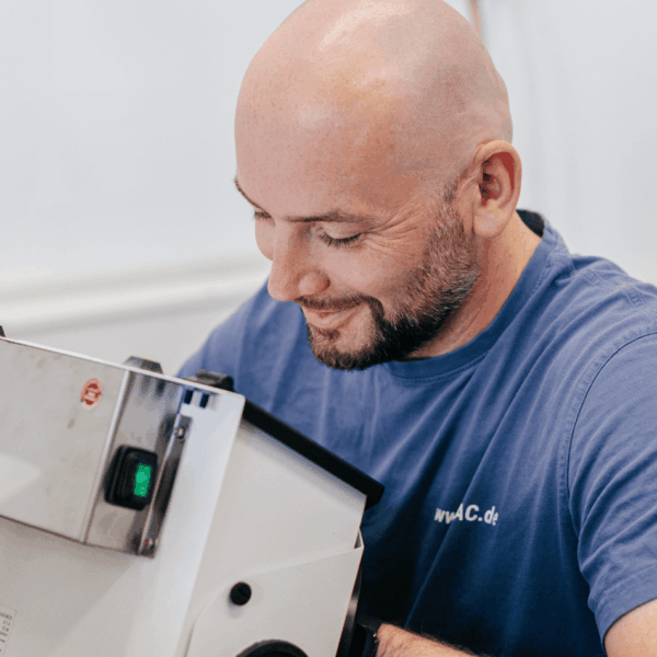 Ein Mitarbeitender von Laser Add Concept sitzt vor einer Schleifmaschine und bearbeitet Bauteile aus Metall nach dem Laserschmelzen