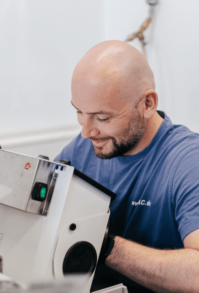 Ein Mitarbeitender von Laser Add Concept sitzt vor einer Schleifmaschine und bearbeitet Bauteile aus Metall nach dem Laserschmelzen