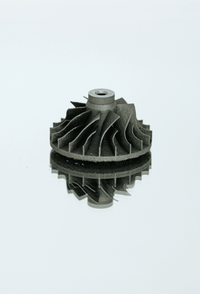 Eine kleine Turbine aus Titan liegt auf einem Spiegel mit neutralem Hintergrund und wurde im SLM Verfahren im Metall 3D Druck gefertigt