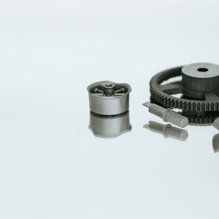 Vier verschiedene Metallbauteile aus dem 3D Druck Metall liegen nebeneinander auf einem neutralen Hintergrund zur Produktveranschaulichung